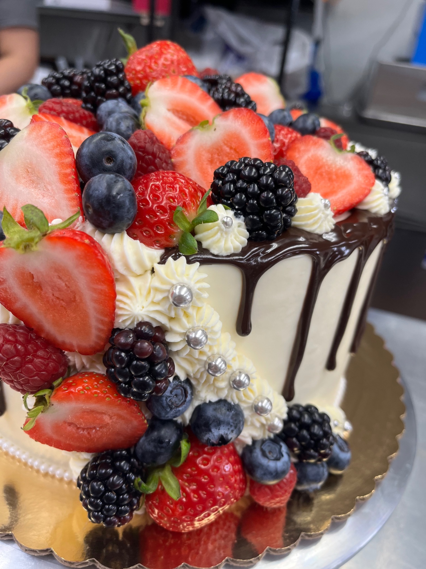 White cake with chocolate drip and fresh berries